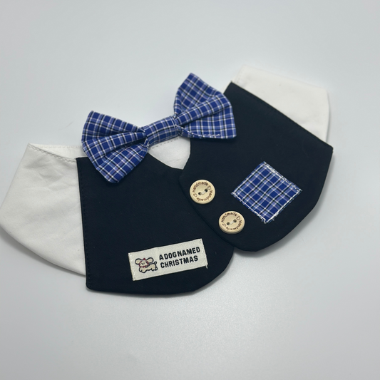 Navy blue pet bib with white collar and blue plaid bow tie on clean white background, featuring "A Dog Named Christmas" label, wooden buttons, and plaid pocket detail 