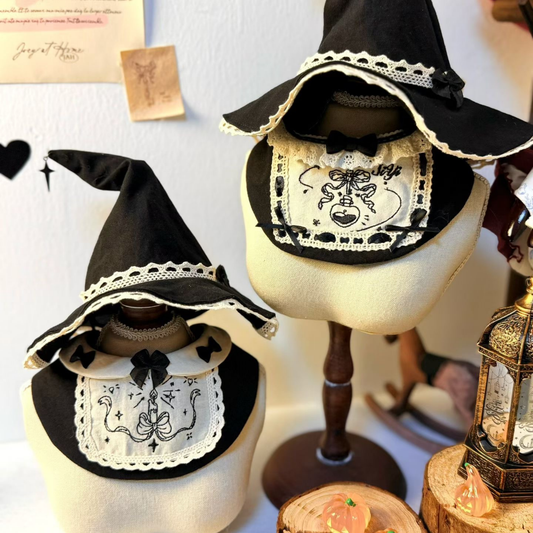 Black witch hats with white lace details on mannequin heads against a neutral background.