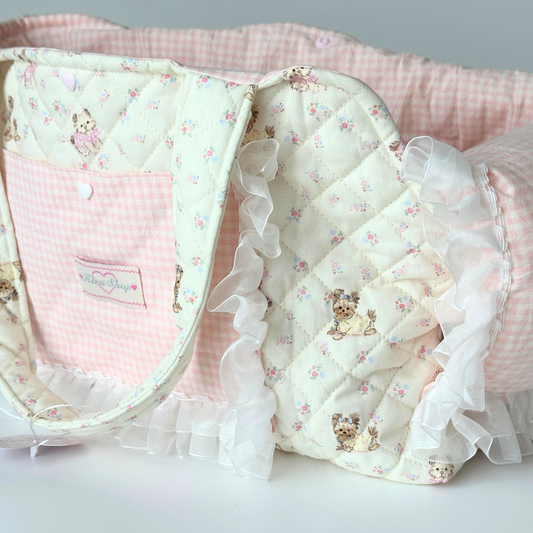 Handmade pet carrier bag featuring pink gingham base with adorable teddy bear and floral print quilted fabric, white ruffle trim details, front pocket with branded label, and comfortable ribbon handles. Premium quality pet travel accessory with soft padding and secure construction, perfect for small dogs, cats, or doll transportation.