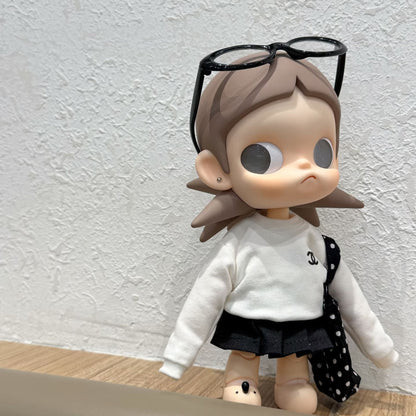 Zsiga doll in Chanel-style white sweater, black pleated skirt and polka dot bag with black sunglasses pushed up on head - full body side view