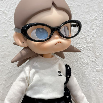 Close-up of Zsiga doll wearing Chanel-style white sweater with black logo, polka dot bag and oversized black sunglasses - front view detail